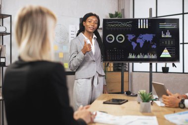 Çekici pozitif gülümsemeli başarılı genç iş kadını, şirketlerin çalışma bilgilerini gösteriyor