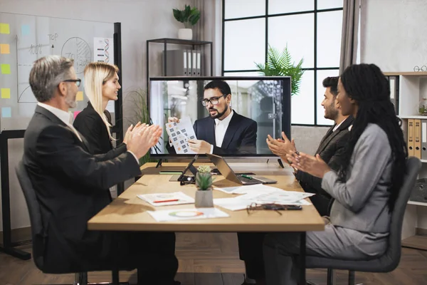 Skupina multietnických podnikatelů tleská rukama a dívá se na obrazovku, má videokonferenci — Stock fotografie