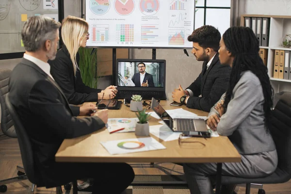 Tým čtyř soustředěných multietnických podnikatelů se dívá na notebook, má videokonferenci — Stock fotografie