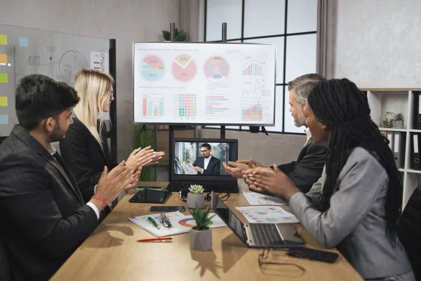 Dört yetenekli çok ırklı iş adamından oluşan bir grup el çırpıyor ve dizüstü bilgisayara bakıyor.