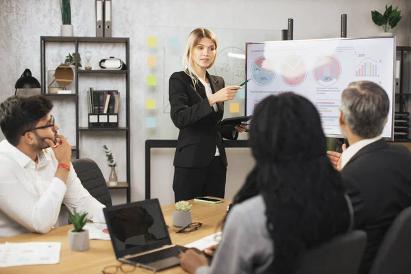 Güzel, motive olmuş, zeki, sarışın, genç iş kadını dijital panoda bilgi paylaşımı yapıyor.
