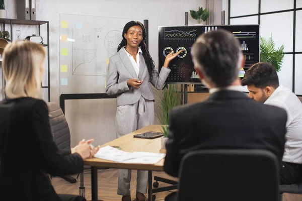 Çekici pozitif gülümsemeli başarılı genç iş kadını, şirketlerin çalışma bilgilerini gösteriyor