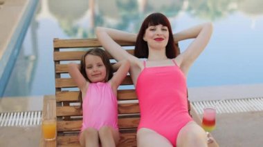 Sevimli kızı olan bir kadın ahşap iskemlede zevkle yatıyor..