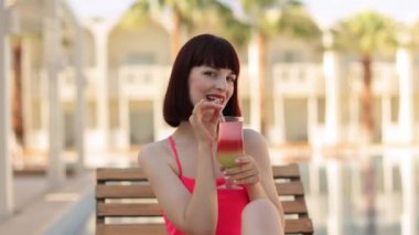 Yaz tatili moda kavramı - bronzlaşmış kadın pembe bikinili mayo giyiyor ve kokteyl camı kullanıyor.