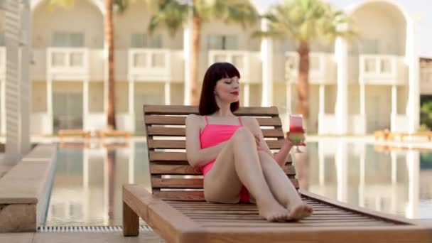 Ritratto di giovane donna in costume da bagno in bikini rosa con bicchiere da cocktail che si rilassa al sole tropicale — Video Stock
