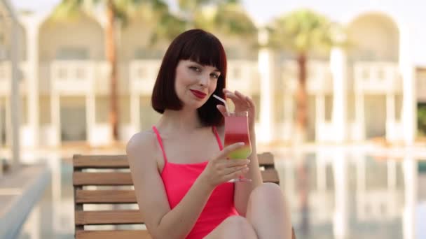 Portrait of young woman in pink bikini swimsuit with cocktail glass chilling in the tropical sun — Stock Video