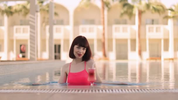 Jolie jeune femme avec boisson dans la piscine, profiter des vacances d'été — Video