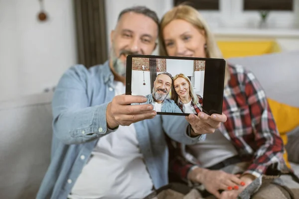 Ευτυχισμένο ώριμο ζευγάρι που παίρνει selfie στο tablet στο σπίτι — Φωτογραφία Αρχείου