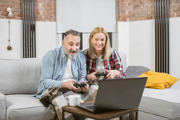 Paar met joysticks en laptop voor het spelen van videospelletjes — Stockfoto