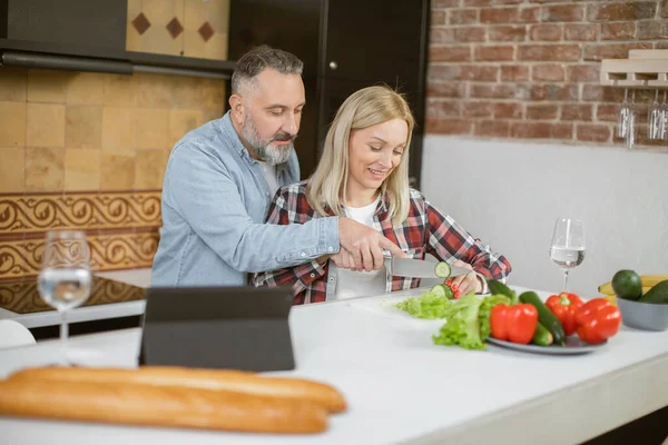 Middle aged family cooking on kitchen and using tablet — стоковое фото