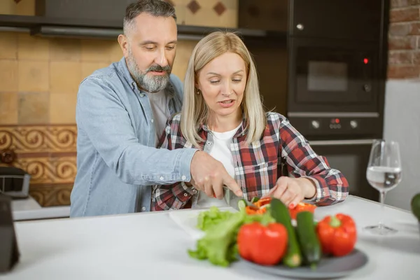 Mature loving couple cooking and using tablet on kitchen — стоковое фото