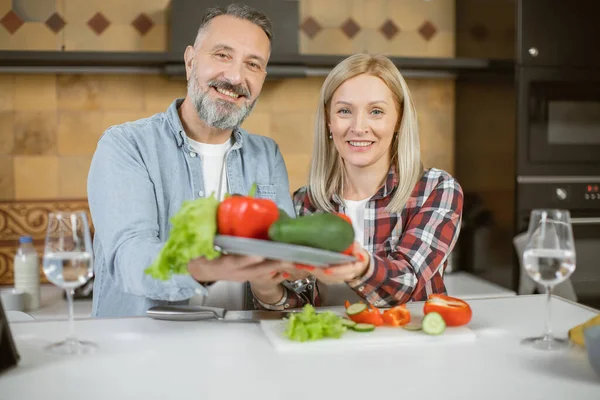 Family standing on kitchen and holding fresh vegetables — Stock Fotó