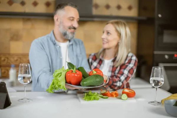Idős pár, akik egészséges zöldséget tartanak a konyhában. — Stock Fotó