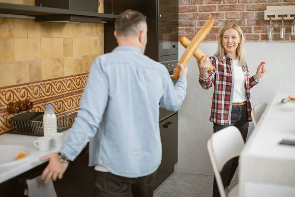 Smiling family having playful fight baguettes on kitchen — Stock Fotó