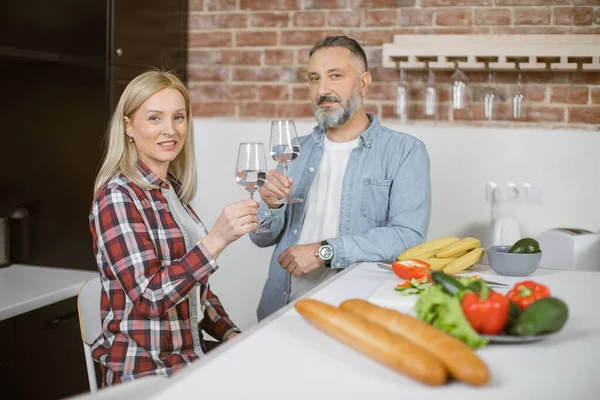 Couple drinking water and looking at camera on kitchen — Stock Fotó