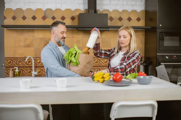 Mature caucasian family unpacking shopping back on kitchen — стоковое фото