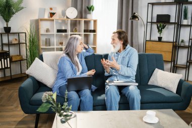 Emekli çift koltukta birlikte otururken dizüstü bilgisayar kullanıyor.