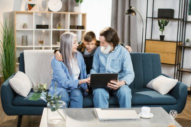 Genç ve mutlu bir torun. Büyükannesine ve büyükbabasına günlük kıyafetleriyle sarılıyor..