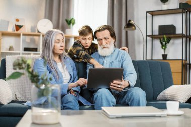 Genç mutlu çocuk ekranda büyükannesi ve büyükbabasına bir şey gösteriyor.