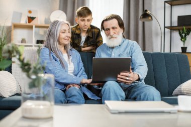 Genç ve mutlu bir torun. Büyükannesine ve büyükbabasına günlük kıyafetleriyle sarılıyor..