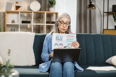 Masada otururken grafikler ve tablolar gösteren neşeli olgun bir kadın..