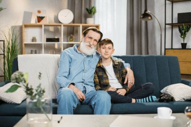 Mutlu büyükbaba kanepede otur ve okul çağındaki torununla evde vakit geçir.