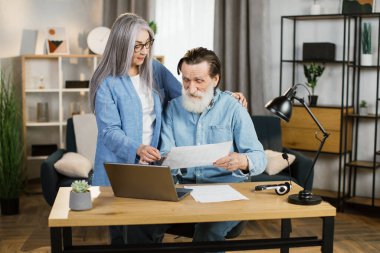 Güzel, olgun bir kadın ve sakallı bir adam birlikte çalışırken dizüstü bilgisayar kullanıyor..