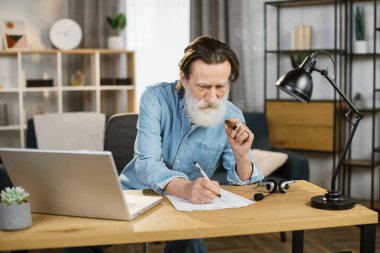 Sert, olgun, gri sakallı, profesyonel yatırımcı, puro içen hissedar.