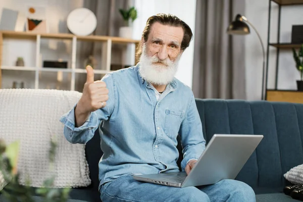Jóképű érett úriember használja laptop videobeszélgetés ül a kanapén a nappaliban otthon — Stock Fotó
