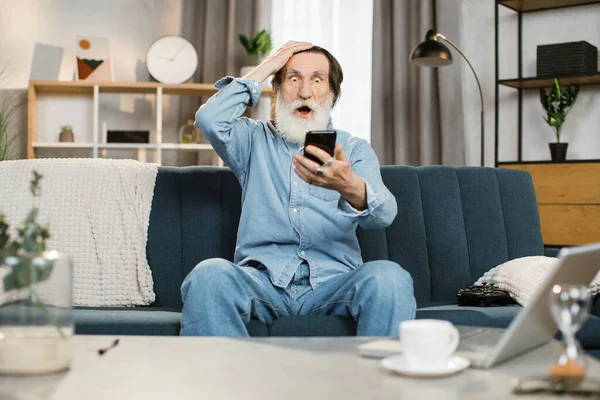 Pensionista con barba gris con cara emocional feliz y puño levantado después de recibir buenas noticias —  Fotos de Stock