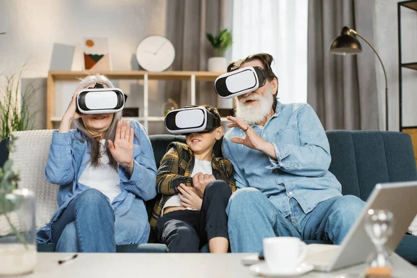 Grand-mère blanche petit-fils et grand-père portant casque vr assis sur le canapé à la maison — Photo