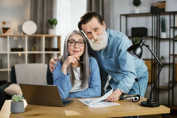 Aydınlık bir evde gündelik giysiler içinde modern aletlerle poz veren pozitif kıdemli karı ve koca..