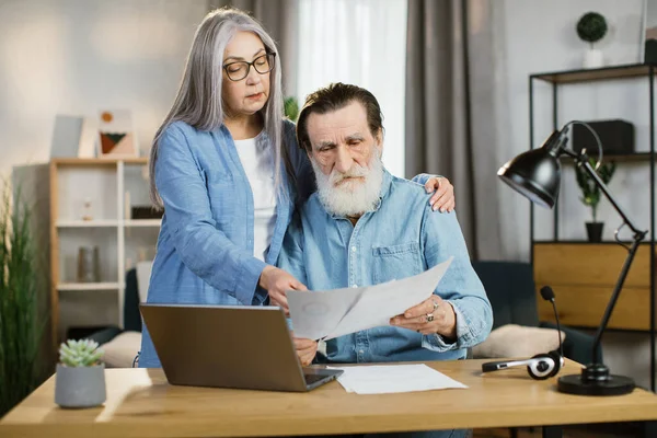Όμορφη ώριμη γυναίκα και γενειοφόρος άνδρας σε casual στολή χρησιμοποιώντας φορητό υπολογιστή κατά τη διάρκεια της εργασίας μαζί. — Φωτογραφία Αρχείου
