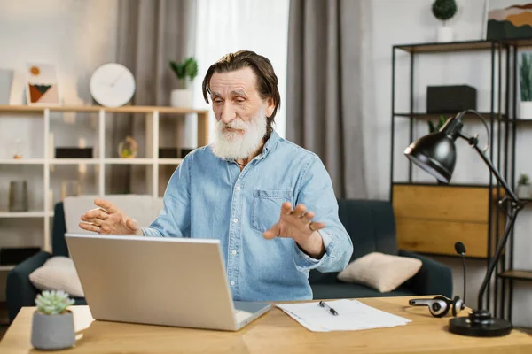 Sonriendo hombre de negocios maduro utilizando el ordenador portátil moderno para el chat de vídeo en el trabajo remoto. —  Fotos de Stock