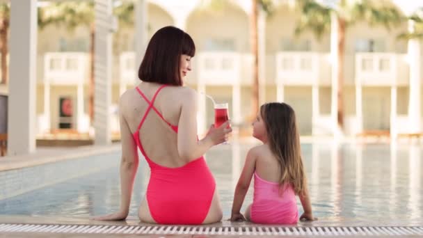 Back view of happy mother and her daughter look at each other while enjoying swimming in pool — Stockvideo