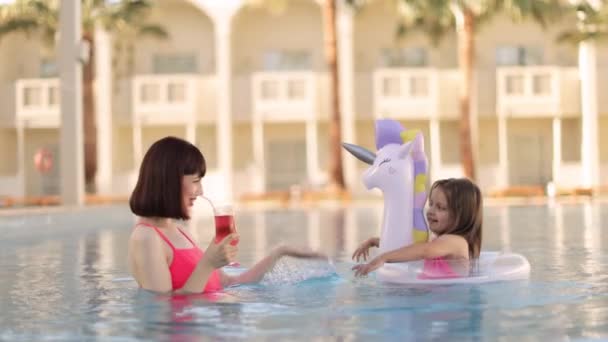 Beautiful mother with her pretty daughter with an inflatable ring in the form of a unicorn — Stockvideo