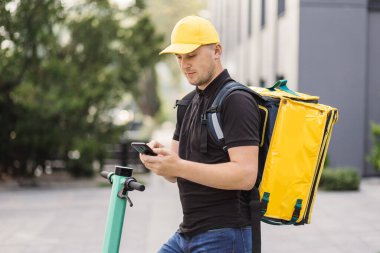 Kurye bir restorandan yemek teslimatı yapmak için cep telefonuna bakıyor..