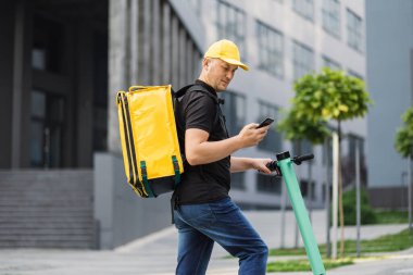 Sarı şapkalı ve termal çantalı bir kurye fast food teslimat servisi yapıyor.