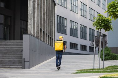 İzotermal yiyecek kutusuyla motosikletli, sarısı maskeli paket servis elemanı..