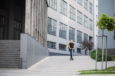 Şehir sokaklarında scooter kullanan bir erkek kurye ve covid salgını sırasında sıcak yemek teslimatı..
