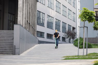 Şehir sokaklarında scooter kullanan bir erkek kurye ve covid salgını sırasında sıcak yemek teslimatı..