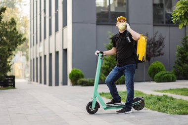 Sarı üniformalı teslimatçı arka planda akıllı bir telefonla duruyor.