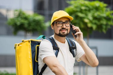 Termal sırt çantalı Kafkas yemek kuryesi sokakta elektrikli scooterla geziyor.