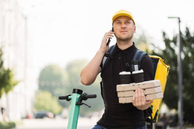 Akıllı telefondan konuşan şapkalı teslimatçı..