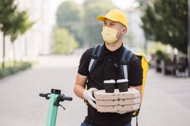 Kurye dışarıda yiyecek ve içecek getiriyor. Şehir caddesinde akıllı telefon kullanan bir adam..