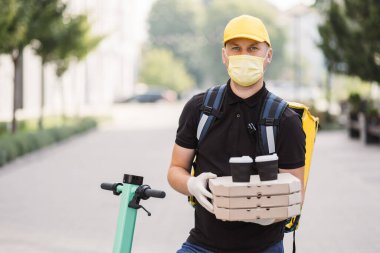Kurye dışarıda yiyecek ve içecek getiriyor. Şehir caddesinde akıllı telefon kullanan bir adam..