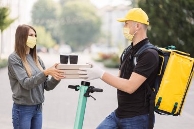 Kurye, beyaz maskeli kız müşteriye pizza ve iki fincan kahve getiriyor..