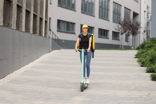 Eşzamanlı sırt çantası taşıyan kurye kadın elektrikli scooterına biniyor.