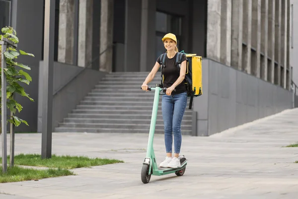 Teslimat, sırt çantalı kadın şehir caddesinde scooter sürüyor.. — Stok fotoğraf