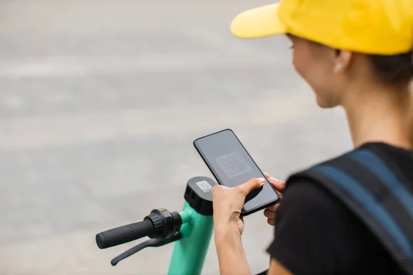 Unrecognizable woman using smartphone for renting modern electric scooter with an application — Zdjęcie stockowe